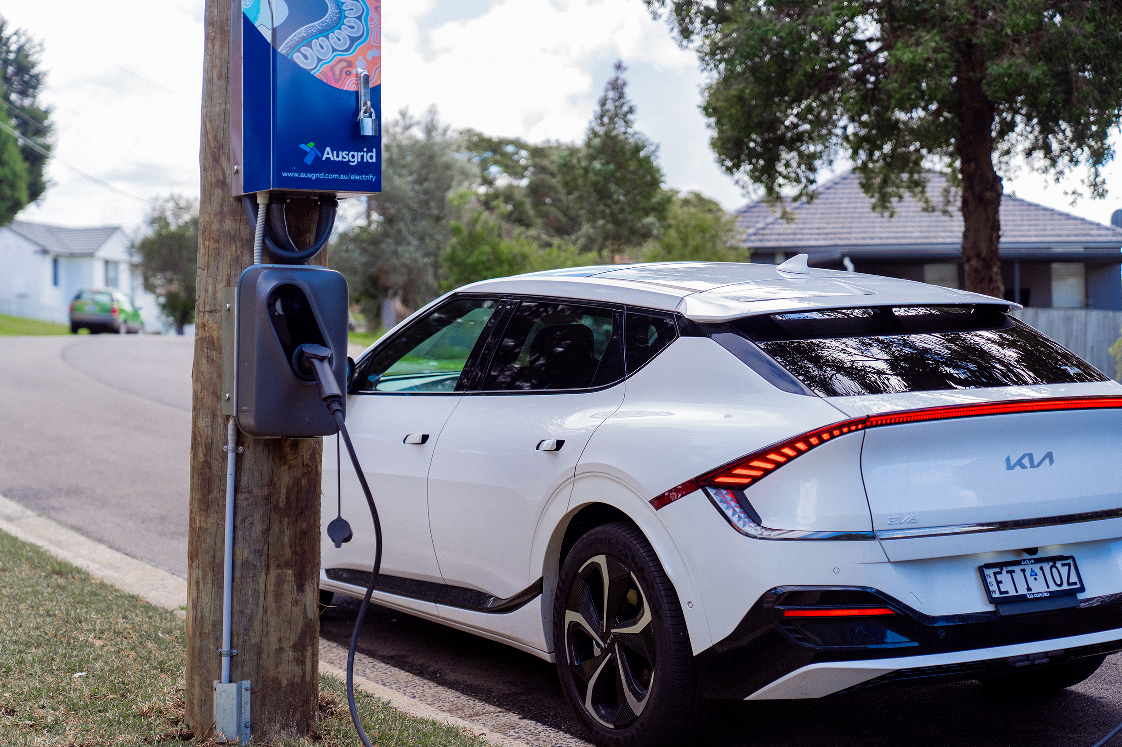Electric vehicle parked on street next to EV charger.