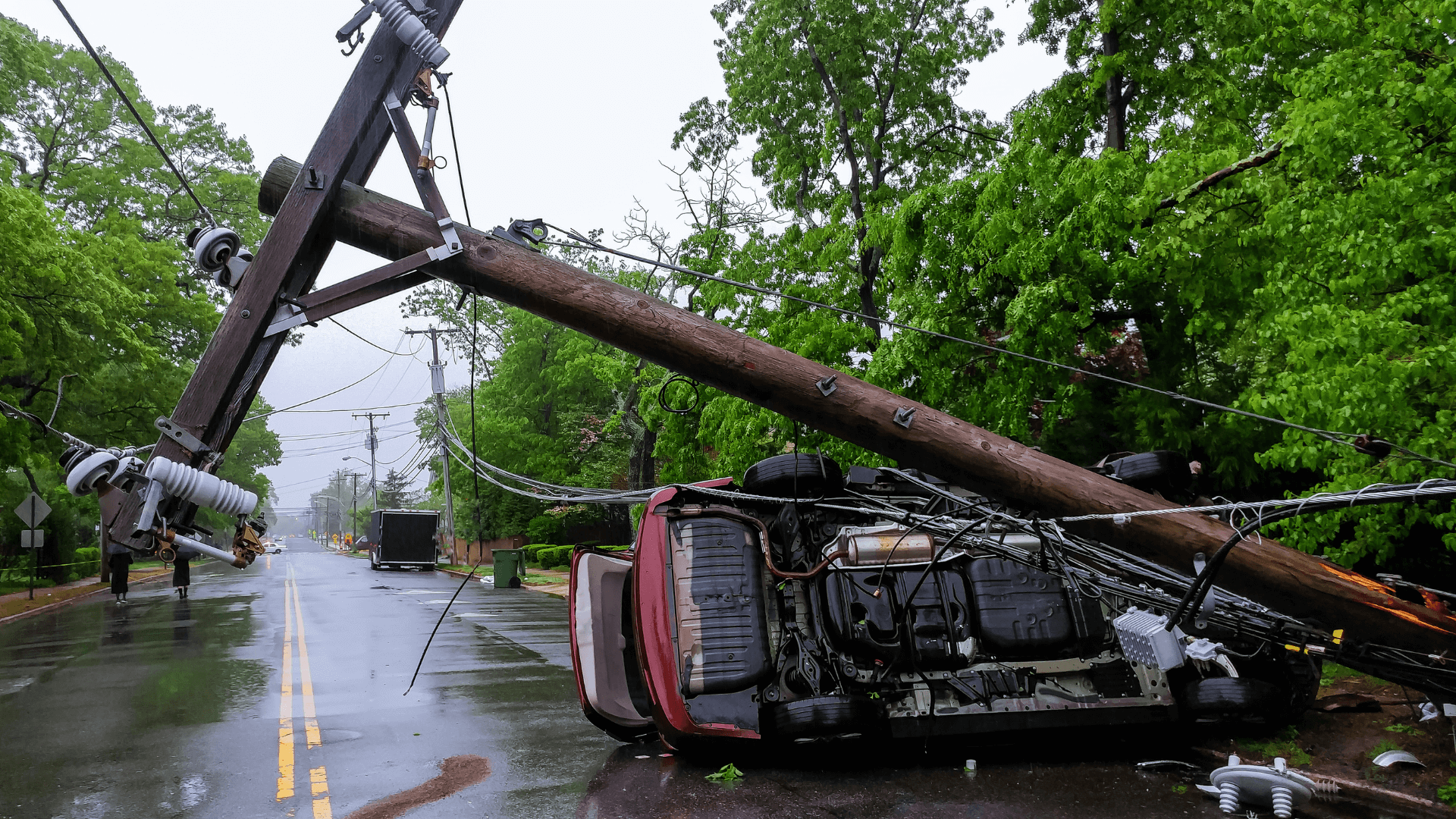 Power pole fallen on flipped car