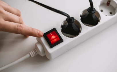 Electricity extension cord with two plugs in, finger on switch